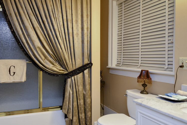 Bathroom decorated with cream walls, a granite white sink, white toilet, and full bath and shower