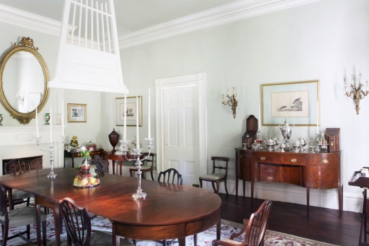 Dining room area decorated with redwood dining table and cabinetry, white walls and trim, dark wood flooring, and an assortment of fruits